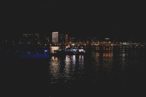 Captivating night view of a cityscape with illuminated buildings and reflections on water.
