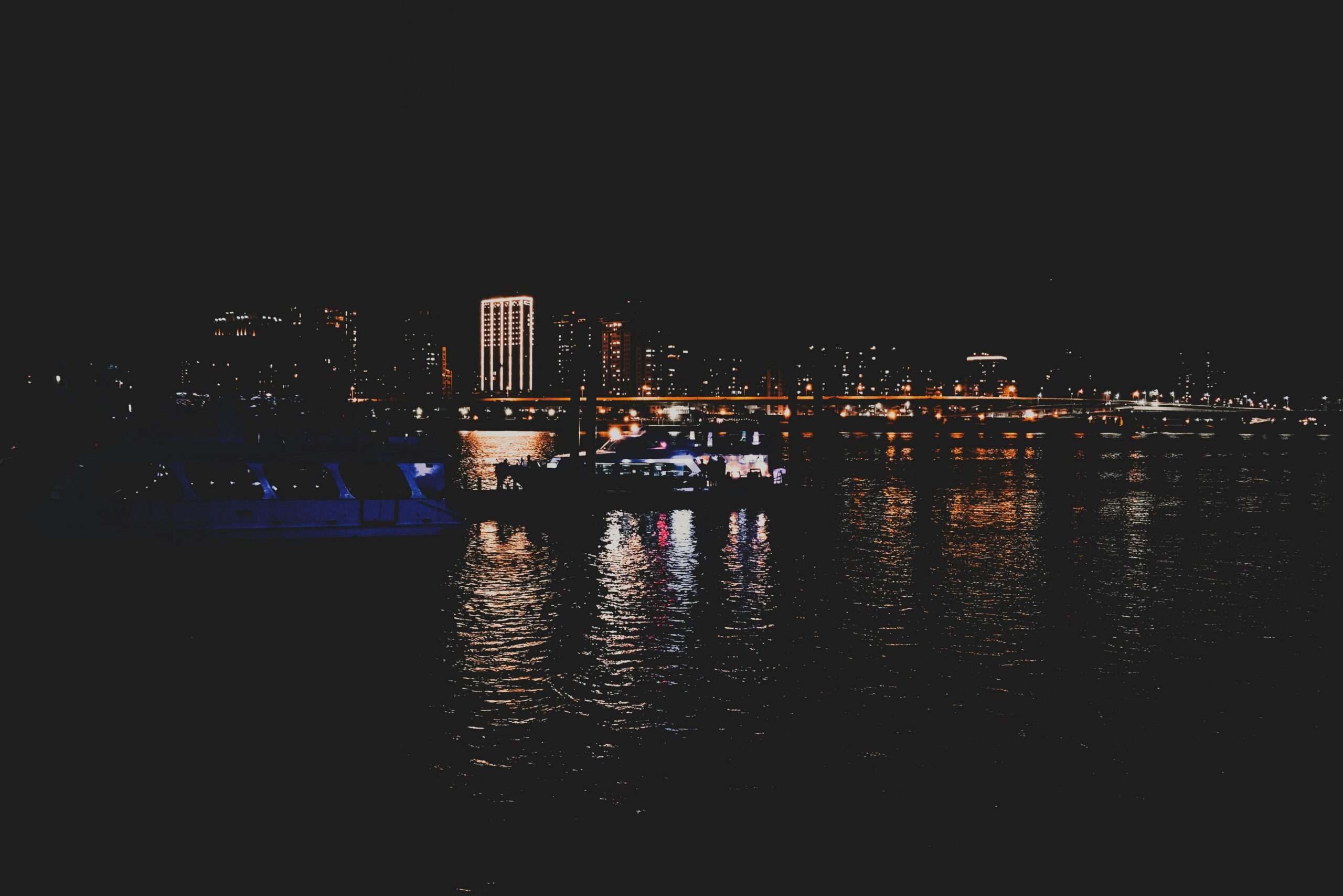 Captivating night view of a cityscape with illuminated buildings and reflections on water.