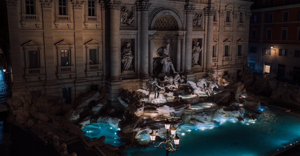 A stunning nighttime view of the illuminated Trevi Fountain, a famous landmark in Rome, Italy.