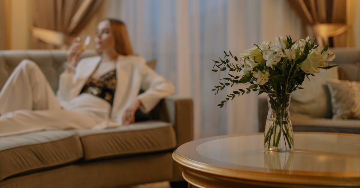 Luxurious hotel room with white flowers and a woman relaxing, creating a serene atmosphere.